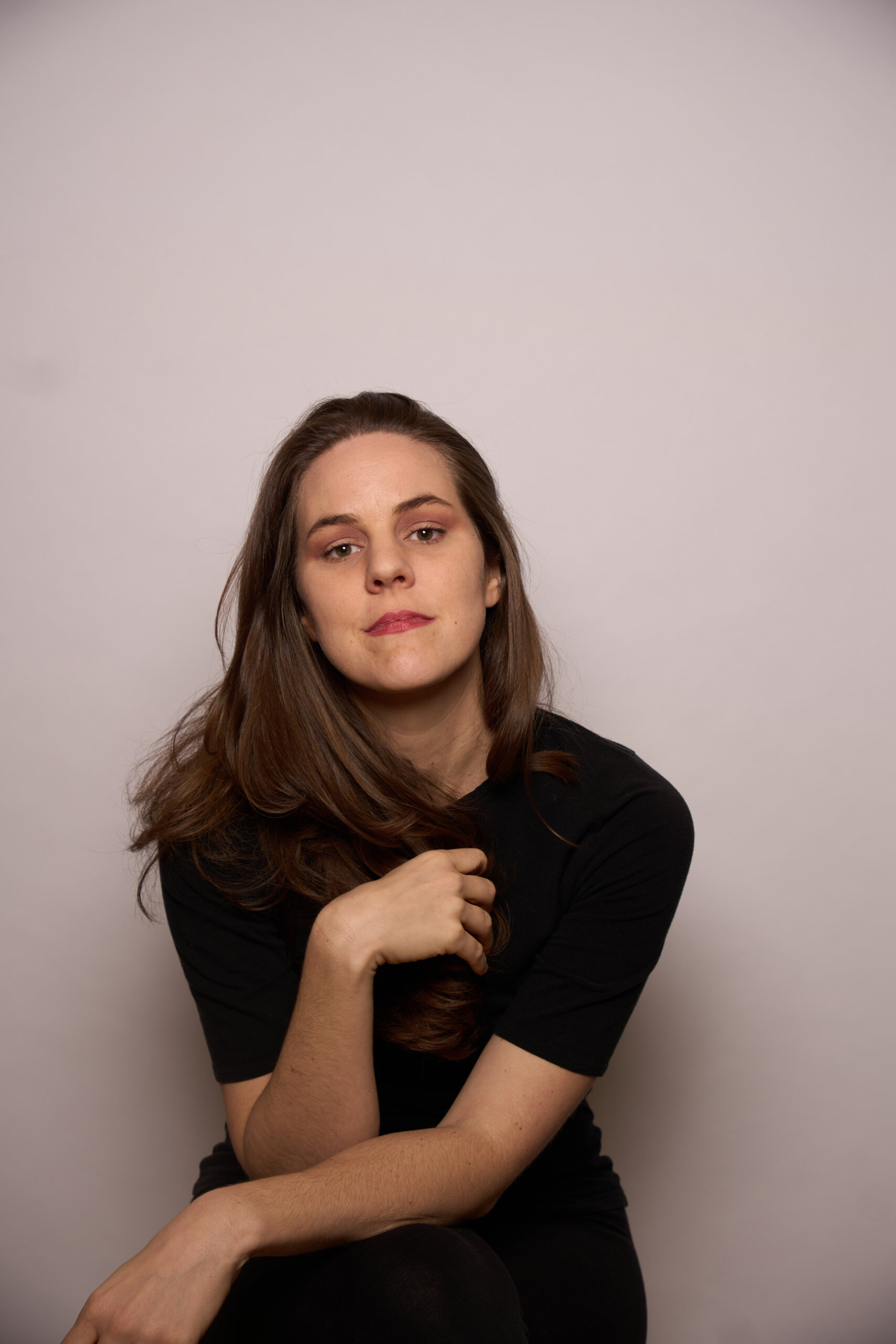 Relaxed studio portrait with a neutral background, suited to a personal brand