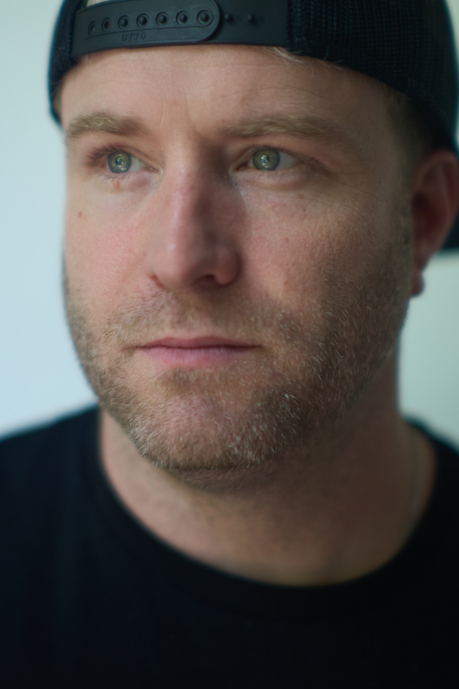 Close portrait of a man in a backwards cap looking off camera