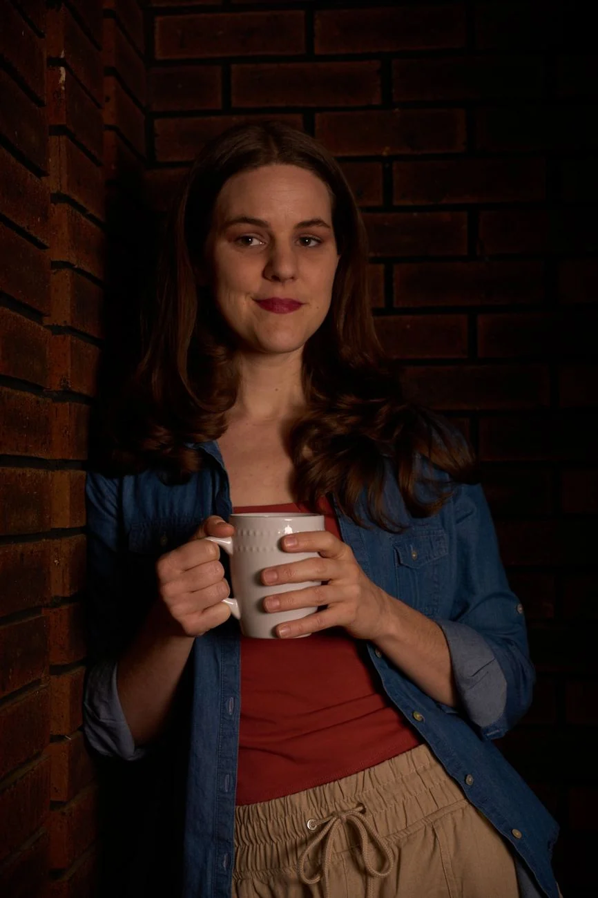 Portrait of a woman holding a coffee mug against a brick wall