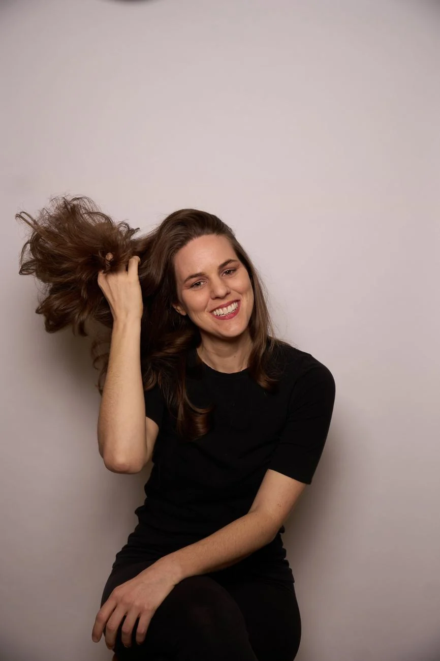 Smiling portrait of a woman playfully lifting her hair
